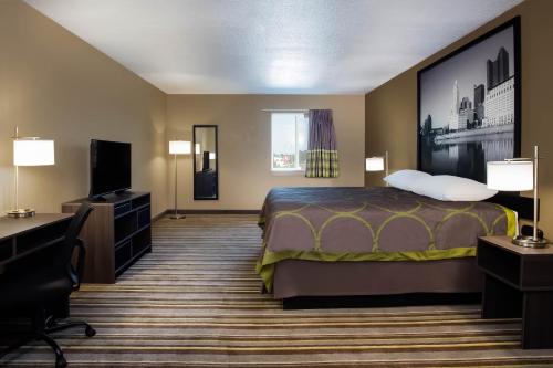 a hotel room with a bed and a flat screen tv at Travel Inn Of Sidney Ohio in Sidney