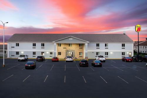 a large building with cars parked in a parking lot at Travel Inn Of Sidney Ohio in Sidney