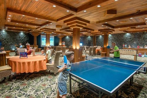 a young boy standing in front of a ping pong table at The Springs Resort & Spa at Arenal in Fortuna