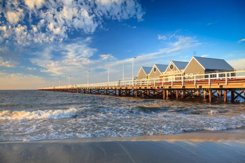 a pier with a row of houses on the water at API Busselton Seaside Escape Apartments in Busselton