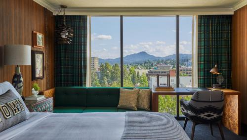 a bedroom with a green couch and a large window at Graduate by Hilton Eugene in Eugene