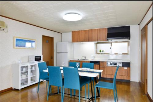 a kitchen with a table and some blue chairs at Wing Mihama in Chatan
