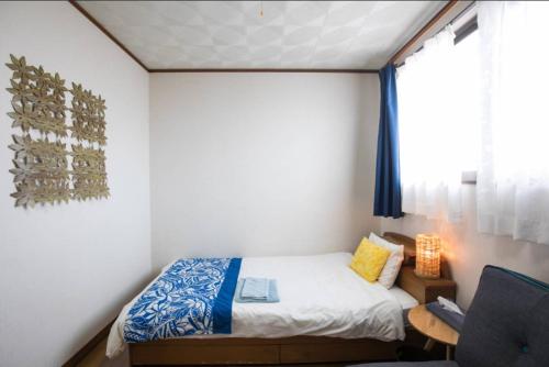 a small bedroom with a bed and a window at Wing Mihama in Chatan