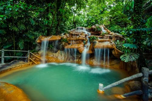 a waterfall in the jungle with a pool of water at The Springs Resort & Spa at Arenal in Fortuna