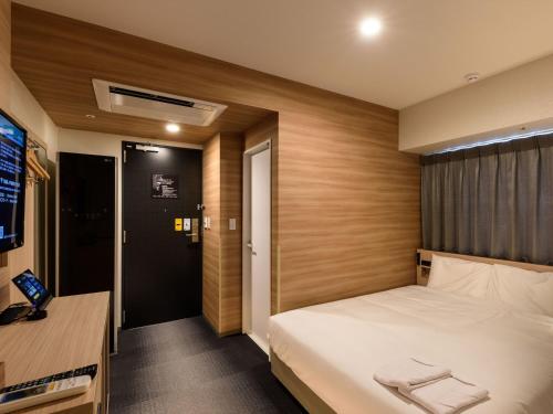 a hotel room with a bed and a television at Henn na Hotel Premier Tokyo Asakusa Tawaramachi in Tokyo
