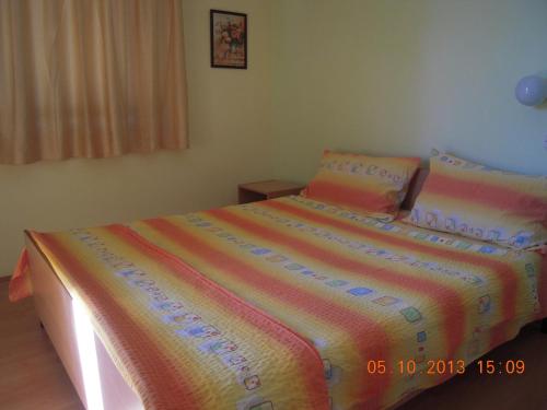 a bedroom with a bed with a colorful blanket at Lile Pestani Accommodation in Peštani