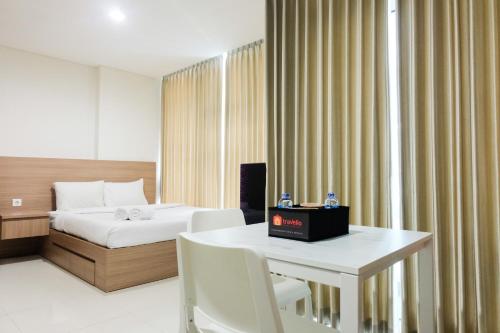 ein Hotelzimmer mit einem Bett und einem Tisch und Stühlen in der Unterkunft Cozy Studio Apartment at Brooklyn Alam Sutera By Travelio in Dongkal Dua