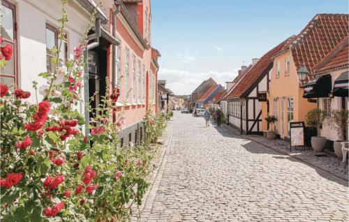 a cobblestone street in a town with red roses at Apartment Nordre Strandvej Iii in Ebeltoft