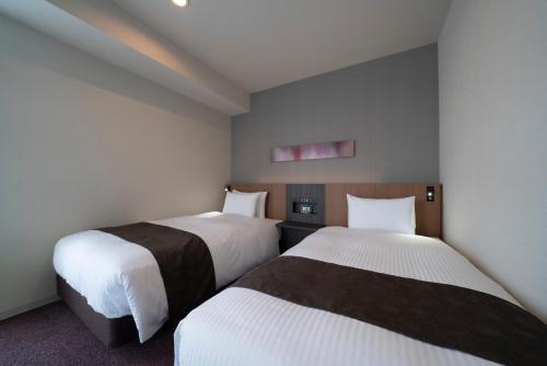 two beds in a hotel room with white sheets at Grand Inn Higashi-Okazaki in Okazaki