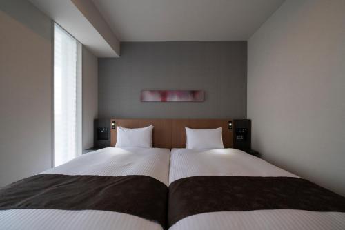 a bedroom with two beds and a large window at Grand Inn Higashi-Okazaki in Okazaki