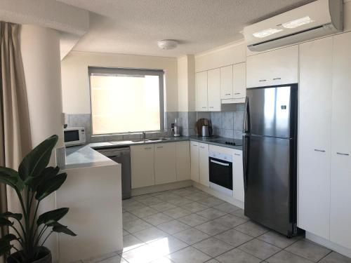 a kitchen with a stainless steel refrigerator and a window at Centrepoint Apartments Caloundra in Caloundra
