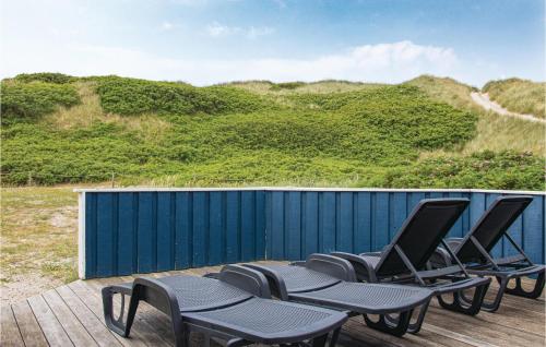 a row of chairs on a deck with a blue fence at Holiday Home Rauhesvej Ix in Bjerregård