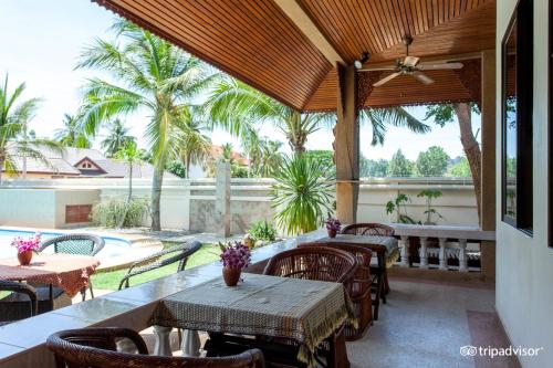 un patio al aire libre con mesas, sillas y palmeras en Long Beach Inn en Sam Roi Yot