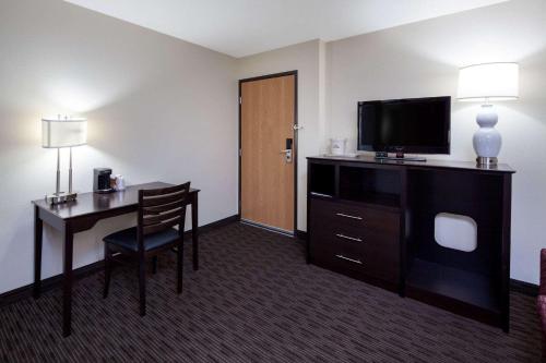 a hotel room with a desk and a flat screen tv at AmericInn by Wyndham Northfield in Northfield