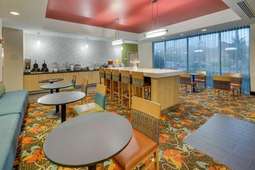 a cafeteria with tables and chairs and a kitchen at La Quinta by Wyndham Starkville at MSU in Starkville