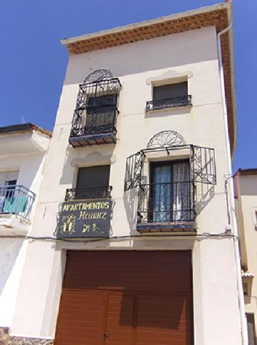 um edifício branco com duas janelas e um sinal nele em Apartamentos Herranz em Alcoroches