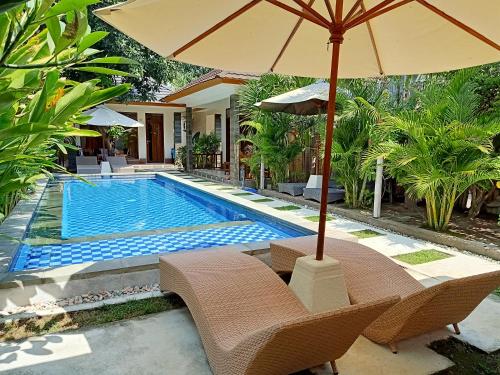 a pool with chairs and an umbrella next to a house at Two Brothers Villa in Gili Islands