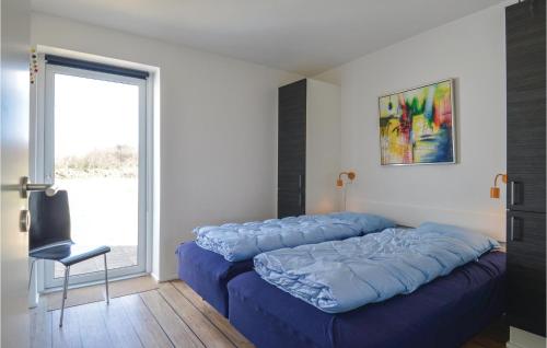 a bed with blue sheets in a room with a window at 3 Bedroom Gorgeous Home In Ringkbing in Hee