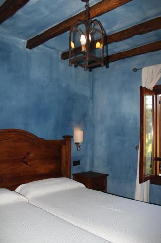 a bedroom with a bed and a blue wall at Posada Calera in Valle De Villaverde