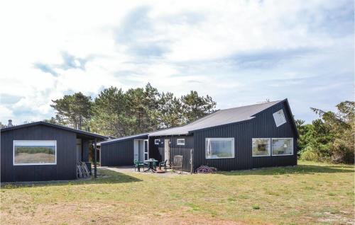 a black house on a grassy field with trees at Three-Bedroom Holiday Home In Hundested in Hundested