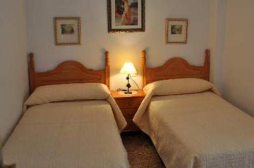 Duas camas num quarto com um candeeiro sobre uma mesa em Apartamentos Herranz em Alcoroches