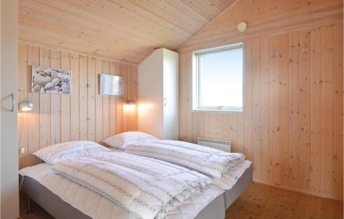 a bed in a room with wooden walls and a window at Søndervig Ferieby in Ringkøbing