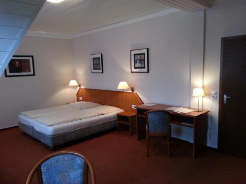 a hotel room with a bed and a desk and a bed and a desk at Hotel Restaurant Klostermühle in Reutlingen