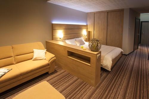 a hotel room with a bed and a couch at Hôtel Restaurant Les Alizés in Lipsheim