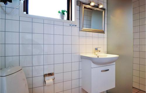 BjerregårdにあるAwesome Home In Hvide Sande With Kitchenの白いタイル張りのバスルーム(洗面台、トイレ付)