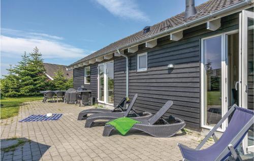 a patio with chairs and tables and a house at Nice Home In Idestrup With Sauna in Marielyst