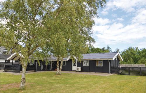 a black house with a tree in the yard at Five-Bedroom Holiday Home In Blokhus in Blokhus