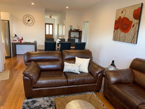 sala de estar con sofá de cuero marrón y mesa en Carpe Diem South #3, en Busselton