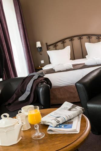 a hotel room with a bed and a table with a glass of orange juice at Hôtel de l'Horloge in Avignon