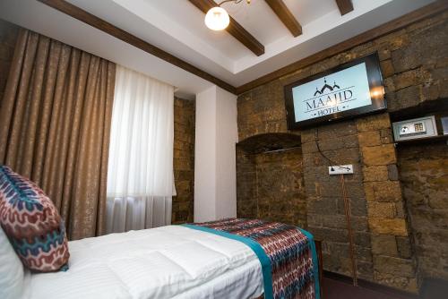 a bedroom with a bed and a tv on a wall at Maajid Boutique Hotel in Baku