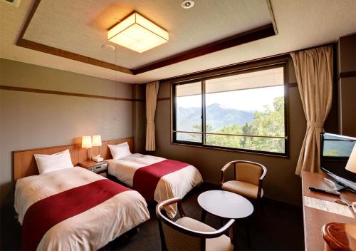 a hotel room with two beds and a window at Shirabiso Kogen Amanogawa in Iida