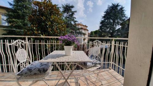 una mesa y sillas con un jarrón de flores en el balcón en Residenza Chiara, en Forlì