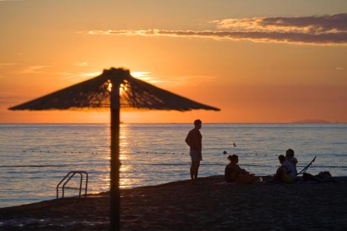 a group of people sitting on the beach at sunset at Hotel Materada Plava Laguna in Poreč