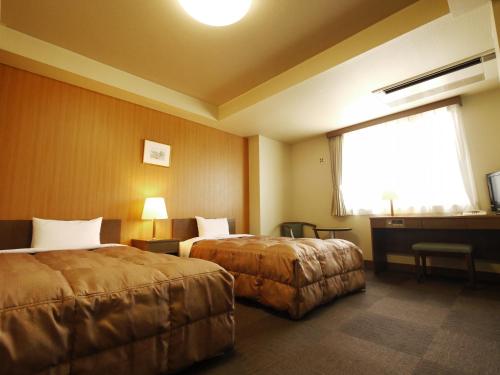 a hotel room with two beds and a window at Hotel Route-Inn Takasaki Eki Nishiguchi in Takasaki