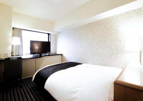 a hotel room with a bed and a flat screen tv at APA Hotel Tokyo Ojima in Tokyo