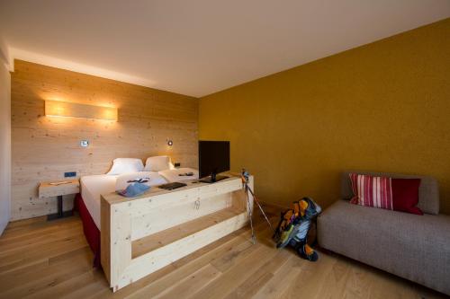 a bedroom with a bed and a couch and a desk at Hotel Dolomitenblick in Terento