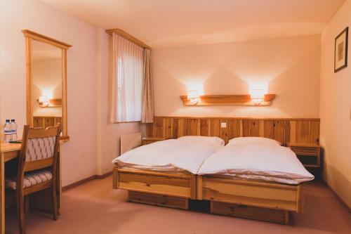a bedroom with a bed and a desk and a mirror at Hotel Europe in Zinal