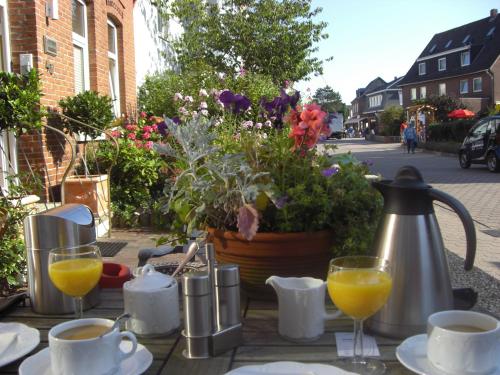 a table with glasses of orange juice and a pot of flowers at Pension Lüttje Meermaid in Borkum