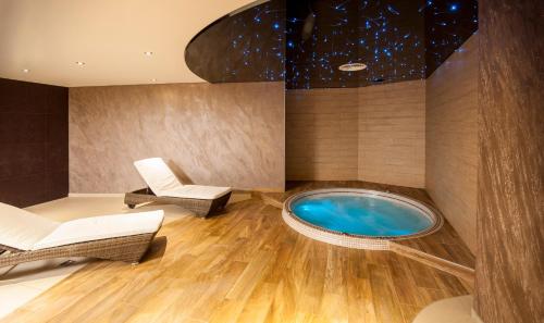 a wellness room with a hot tub and chairs at Hôtel Restaurant Les Alizés in Lipsheim