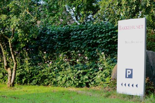 a sign for a park in front of a hedge at Bakkehuset Countryhouse in Skovby