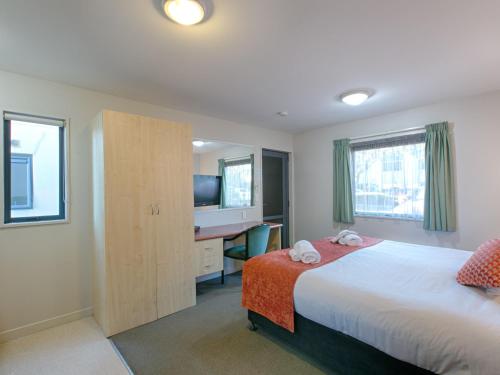 a bedroom with a bed and a desk and a television at Bella Vista Motel Blenheim in Blenheim