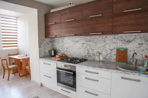 a kitchen with white cabinets and a sink and a stove at MANGO- апартаменты БЕЛЫЕ НОЧИ в Кобрине in Kobryn