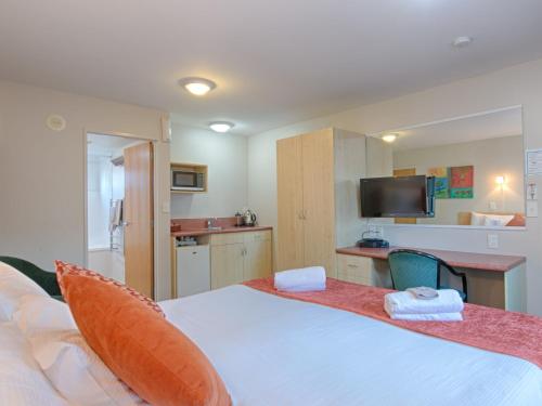 a bedroom with a large white bed and a kitchen at Bella Vista Motel Blenheim in Blenheim