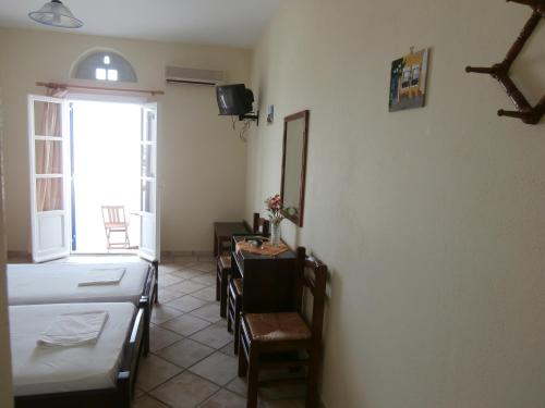 a room with two beds and a table and chairs at Galini Bungalows in Kionia