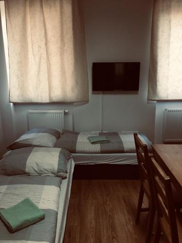 two beds in a room with a desk and a tv at Penzión Petrov grunt in Košúty
