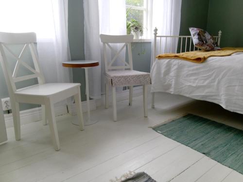 a bedroom with two white chairs and a bed at The Garden Hill Hotel in Vallåkra